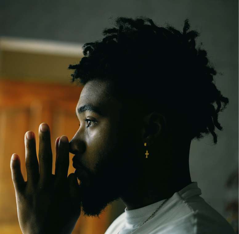 A young African American man in the midst of prayer.